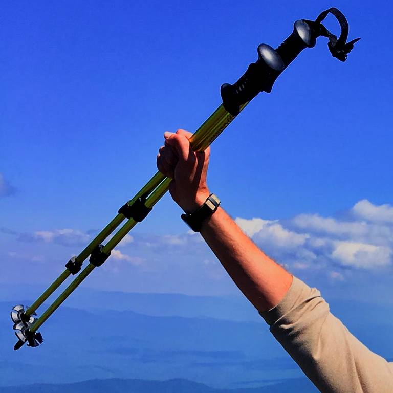 An outstretched arm holding a pair of hiking poles.