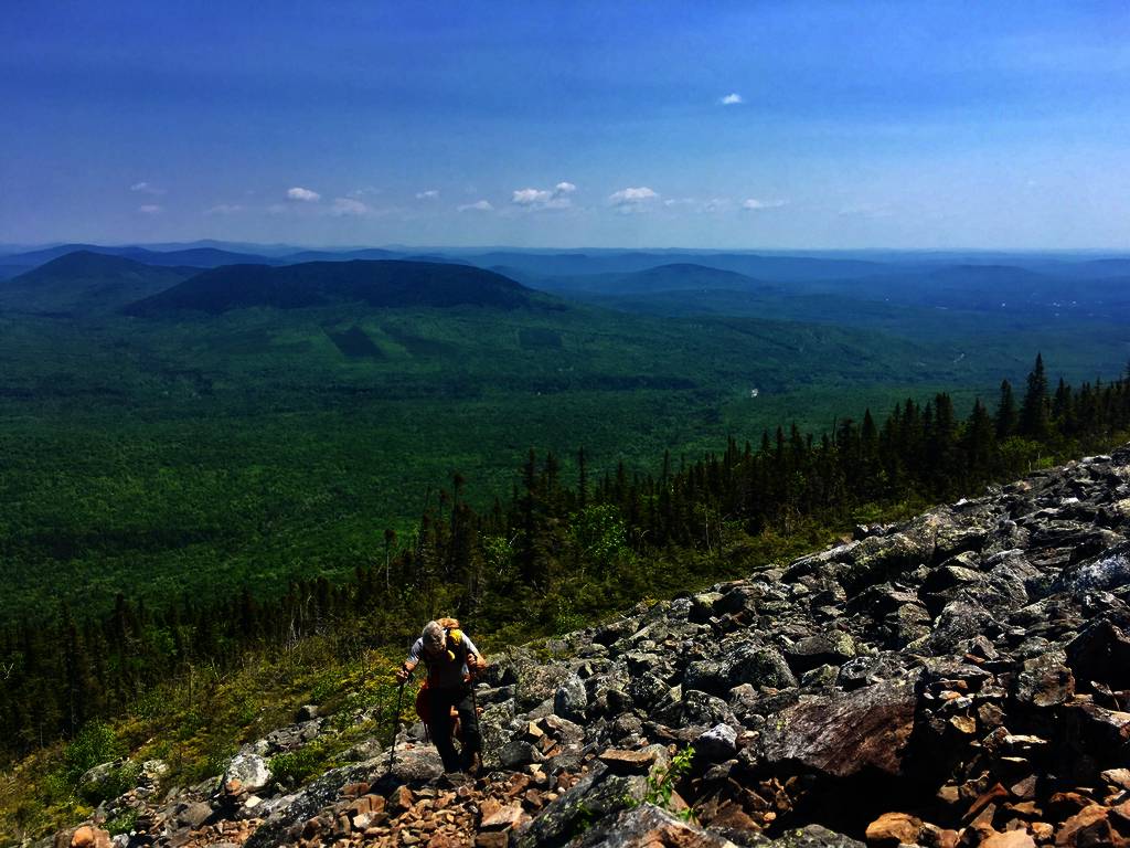 a hiker climbing the a rocky trail on a mountain side