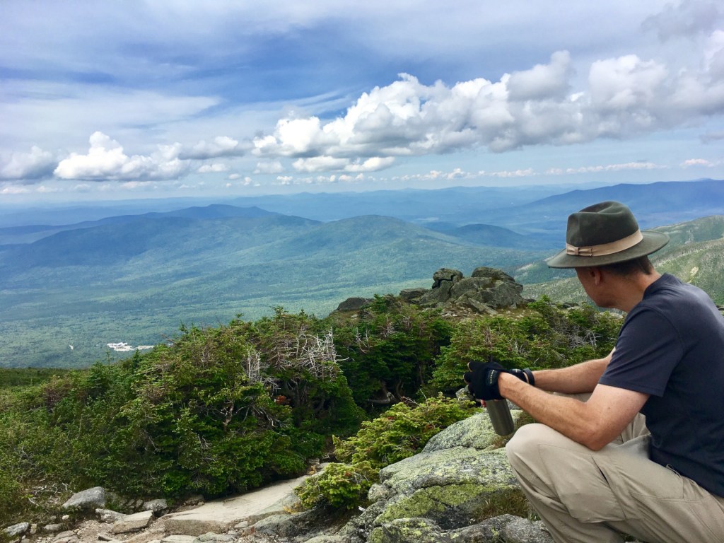 A hiker seated looking at a mountain range in the distance