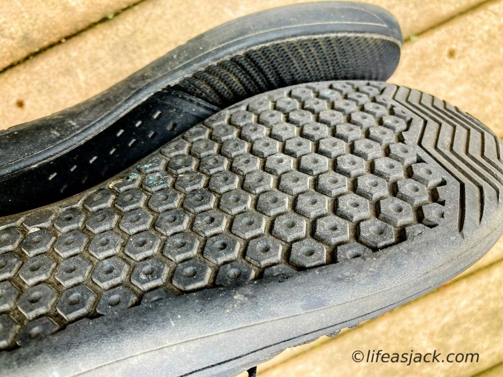A closeup of the soles of a pair of black cross training shoes, showing a hexagonal pattern.