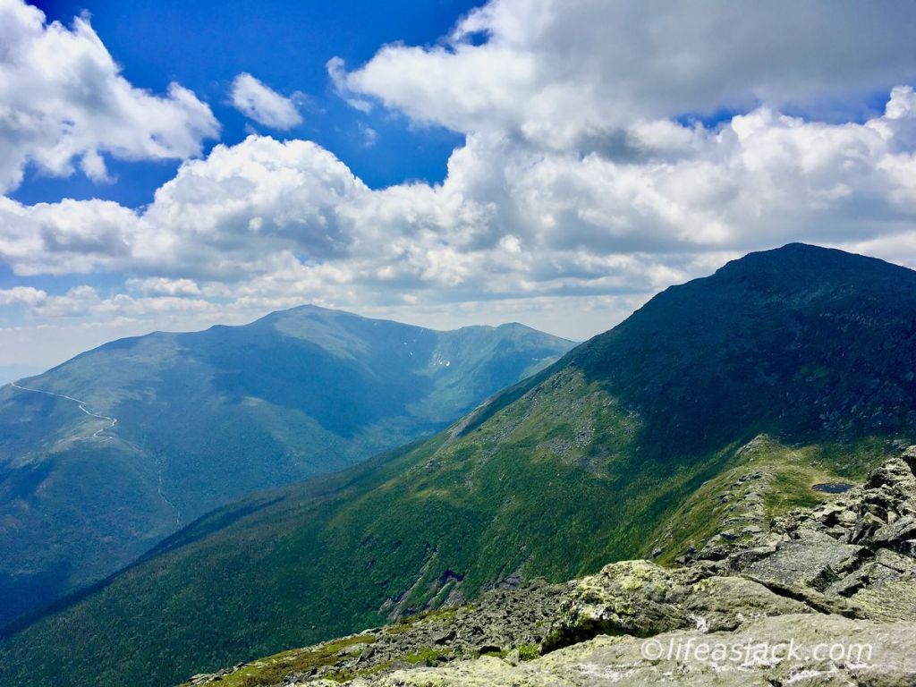 Puffy clouds and ble skies hover over dark blue and green mountain of the Presidential Range in New Hampshire USA