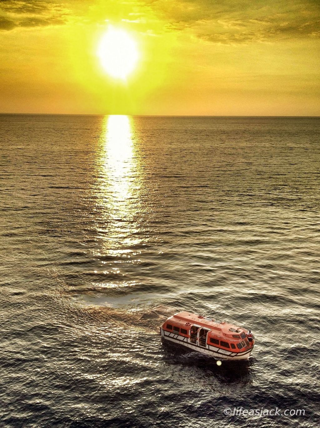 a lifeboat adrift at sea, the sun sinking below the horizon.