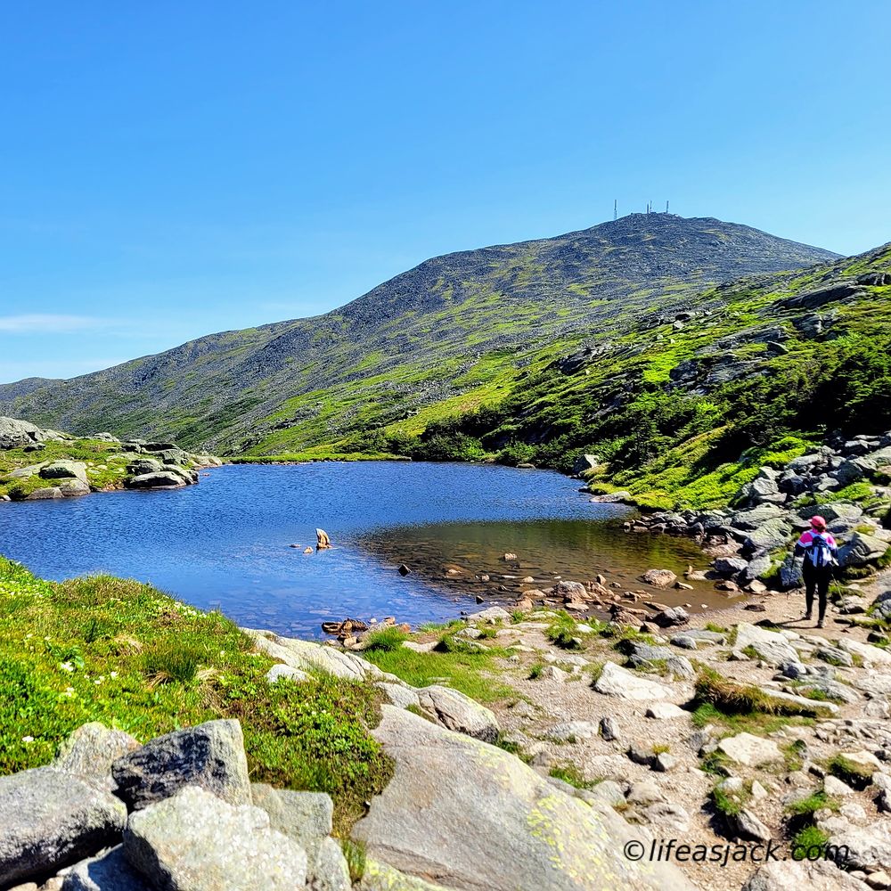 a hiker travels by a mountain lake new Mount Washington in New Hampshire USA