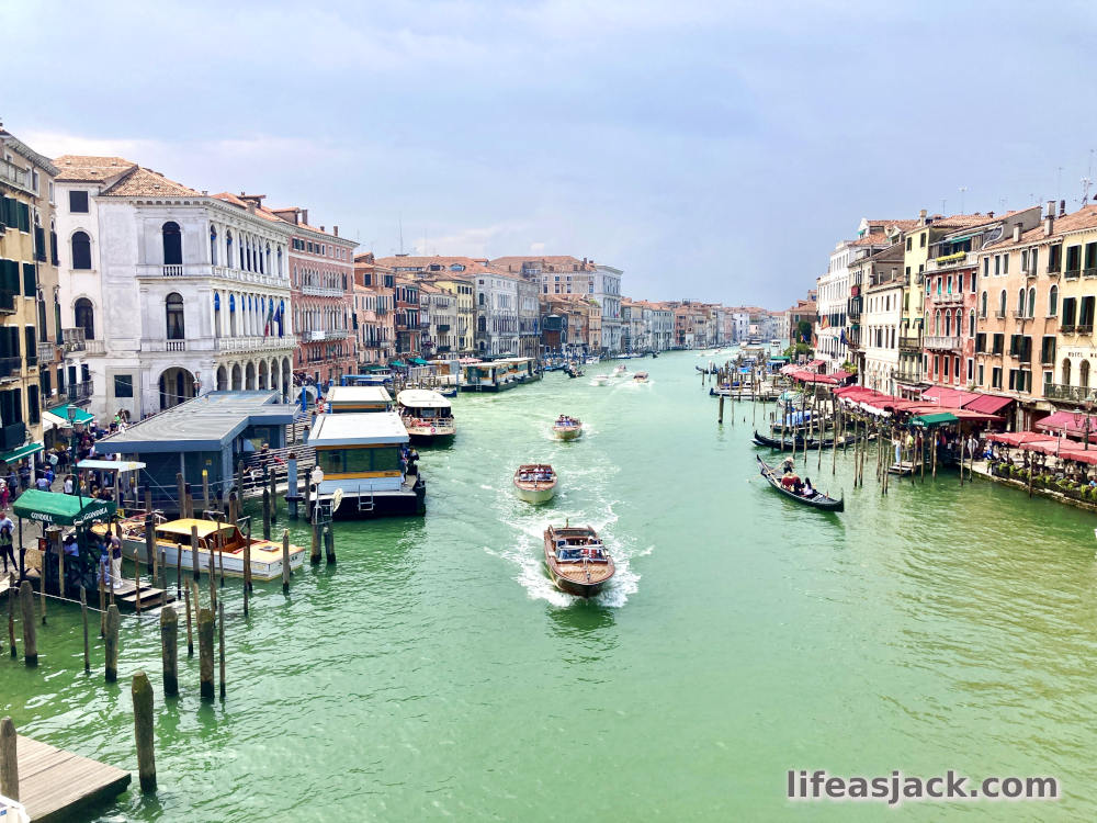 boats travel through the canals of Venice beneath the Rialto bridge