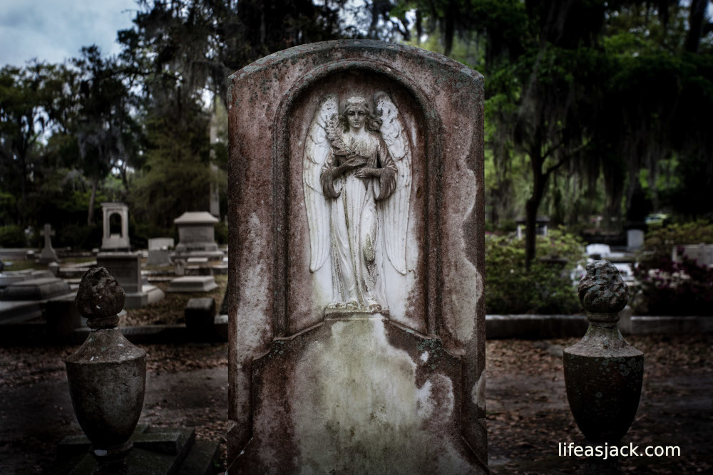 weathered cemetery monument with an angel holding flowers