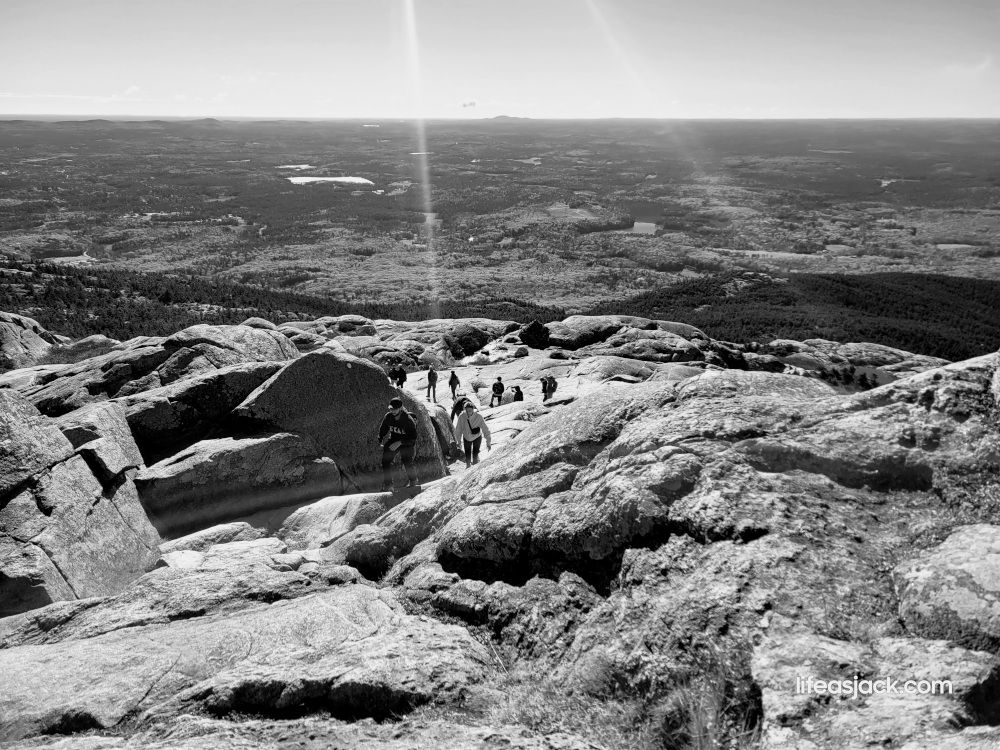 black and white image of hikers climbing steep rocky ledges.
