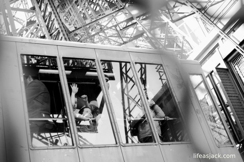 A small boy looks out the window of the Eiffel Tower elevator