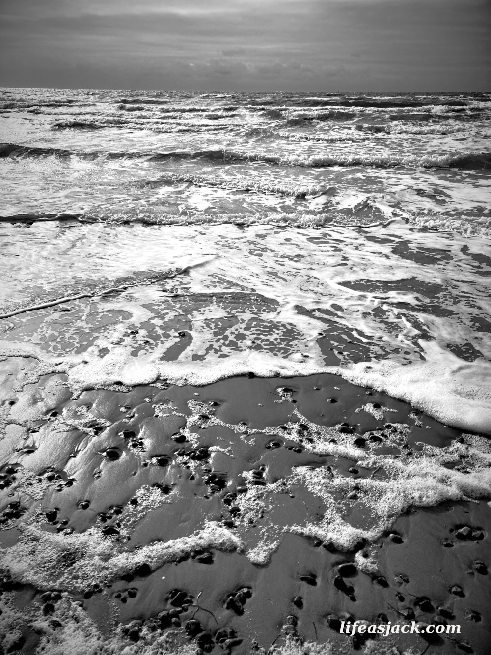 a black and white image of waves crashing on a rocky beach